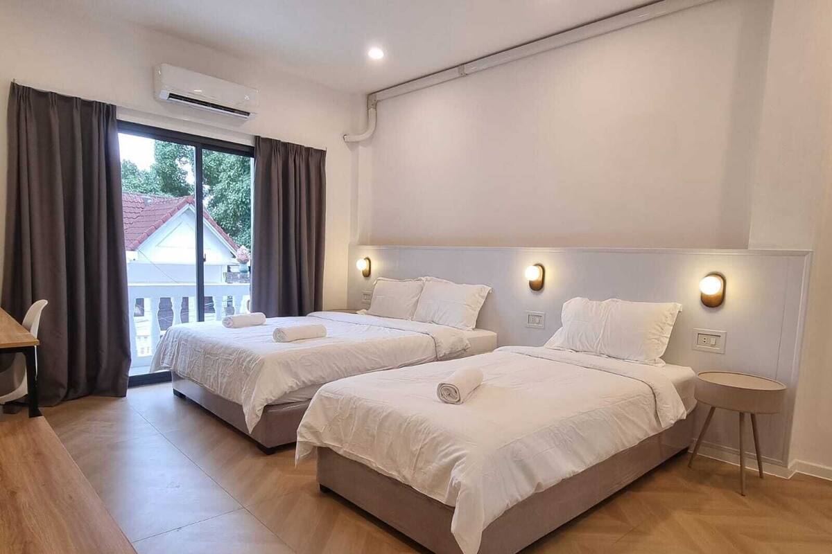Une chambre d’hôtel avec deux lits, un bureau et une vue sur un bâtiment à l’extérieur.