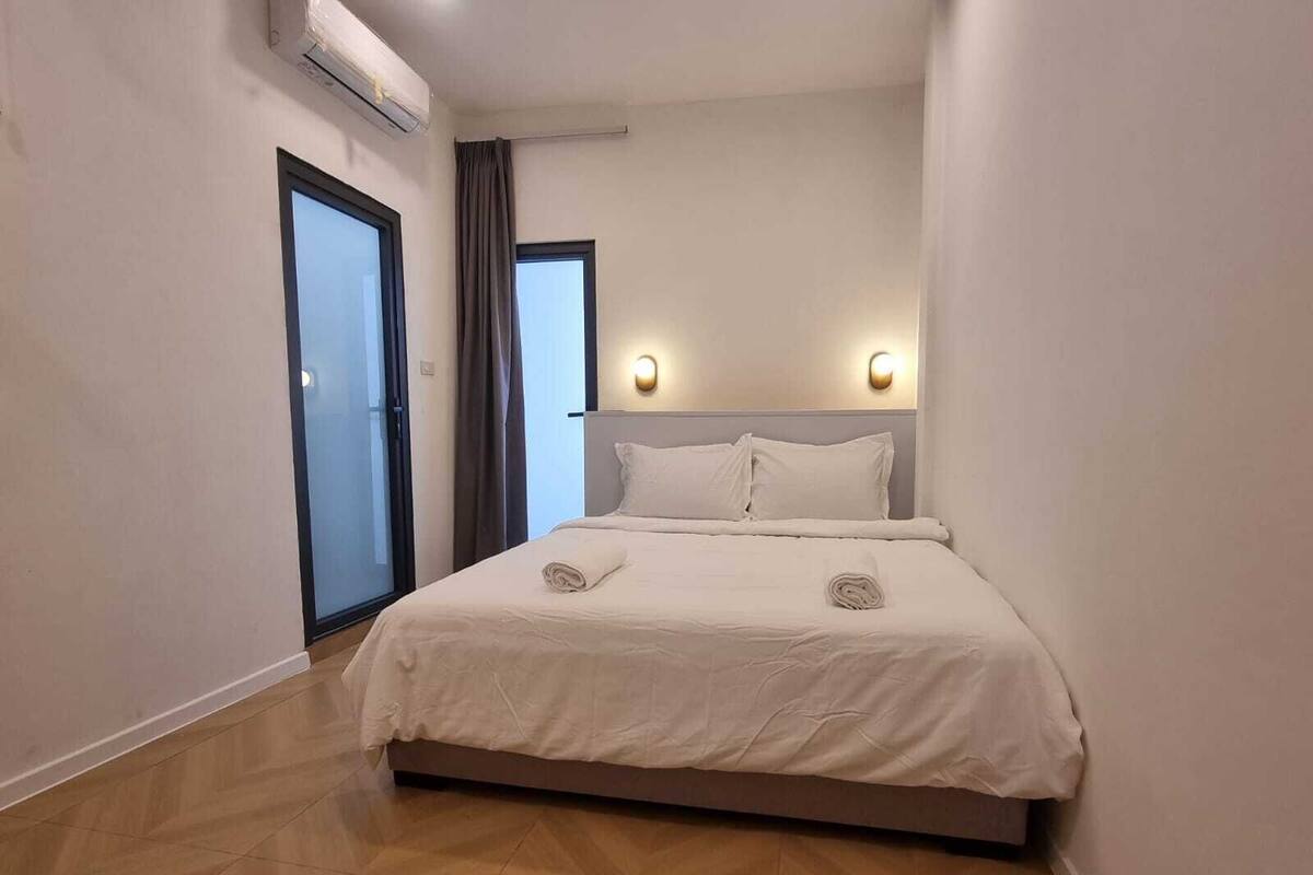 Une chambre d’hôtel moderne avec un grand lit, une porte coulissante et un climatiseur fixé au plafond.