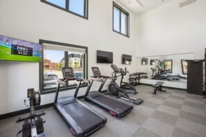 Un gimnasio con cintas de correr, elípticas y pesas libres.