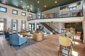 A spacious, multi-level living area with a staircase, seating arrangements, and a kitchen area.