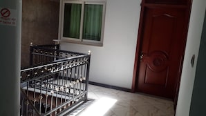 A staircase with ornate metal railings, a wooden door, and a window with green curtains. - Melat Guest House (Addis Ababa)