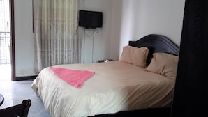 A bedroom with a bed, a television mounted on the wall, and a window with curtains. - Melat Guest House (Addis Ababa)