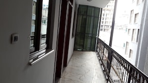 A corridor with a marble floor, a door with a green curtain, and a balcony with a black railing. - Melat Guest House (Addis Ababa)