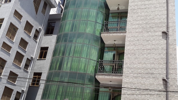 A multi-story building with a green cylindrical structure, multiple windows, and a textured facade. - Melat Guest House (Addis Ababa)