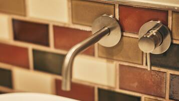 A bathroom with a modern faucet and a tiled wall.