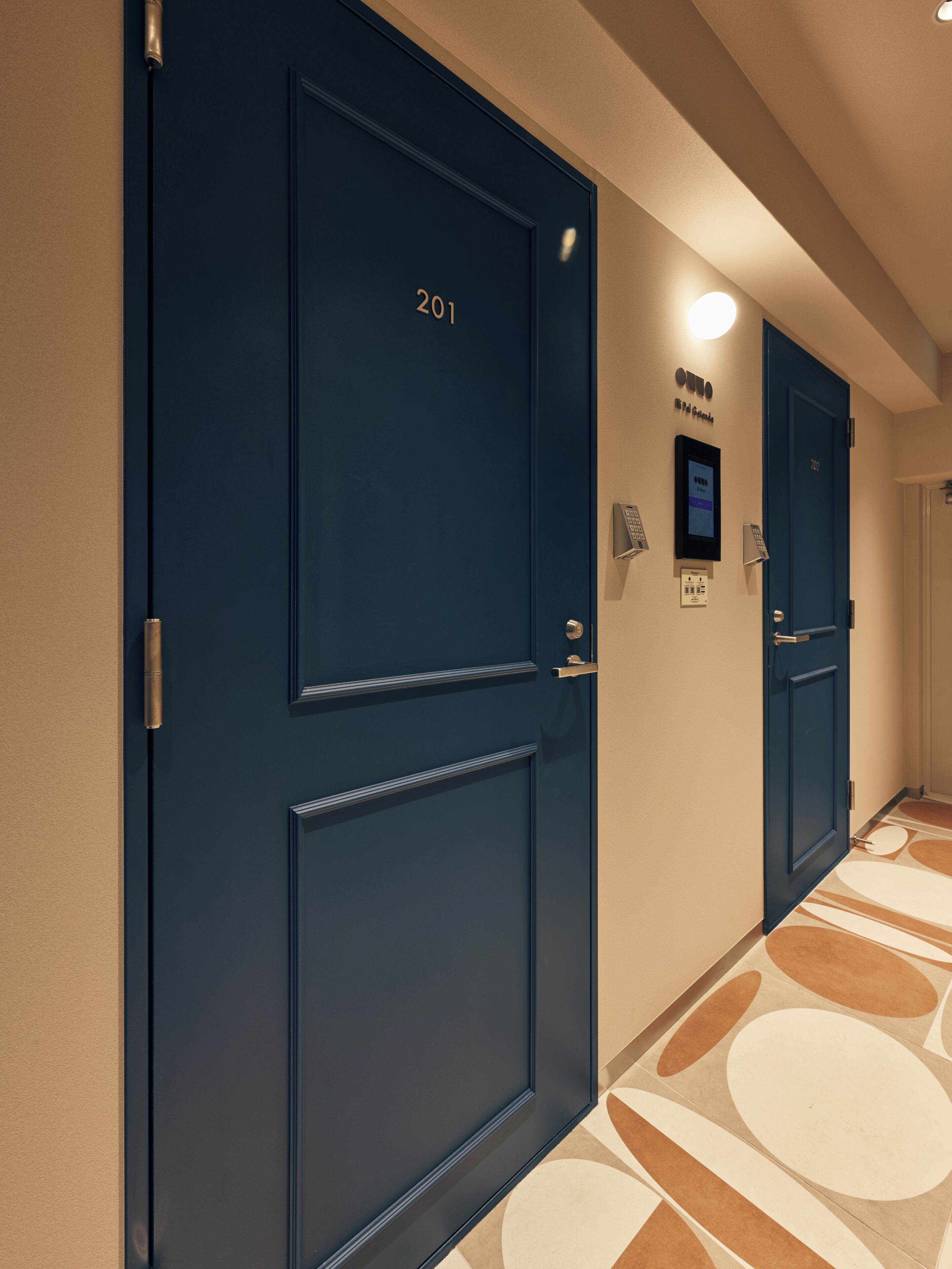 A hallway with dark blue doors, numbered 201, and a wall-mounted phone.