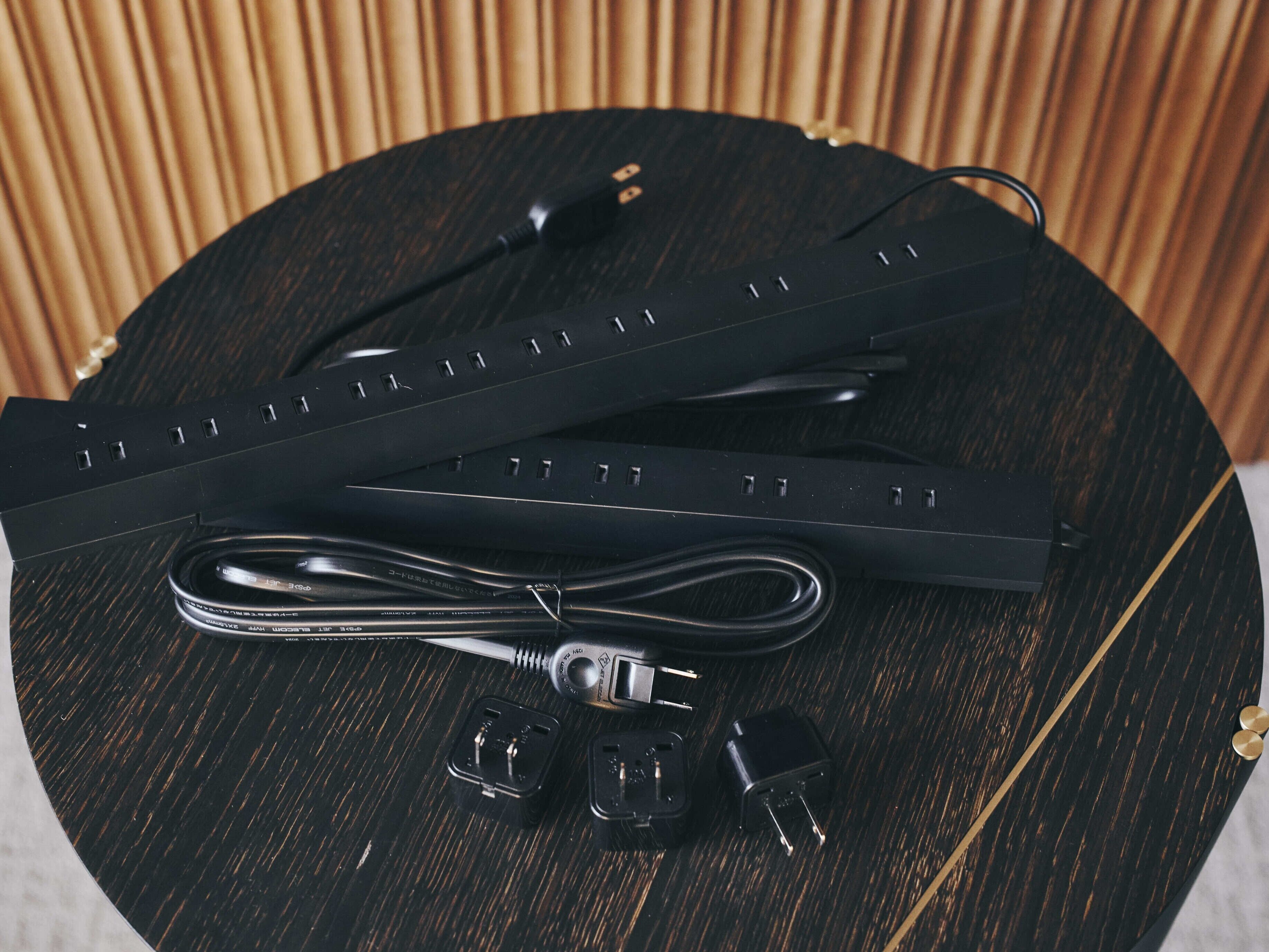 A black cable with a USB connector and a power adapter on a round wooden table.