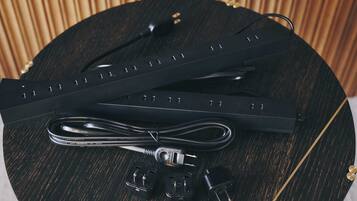 A black cable with a USB connector and a power adapter on a round wooden table.