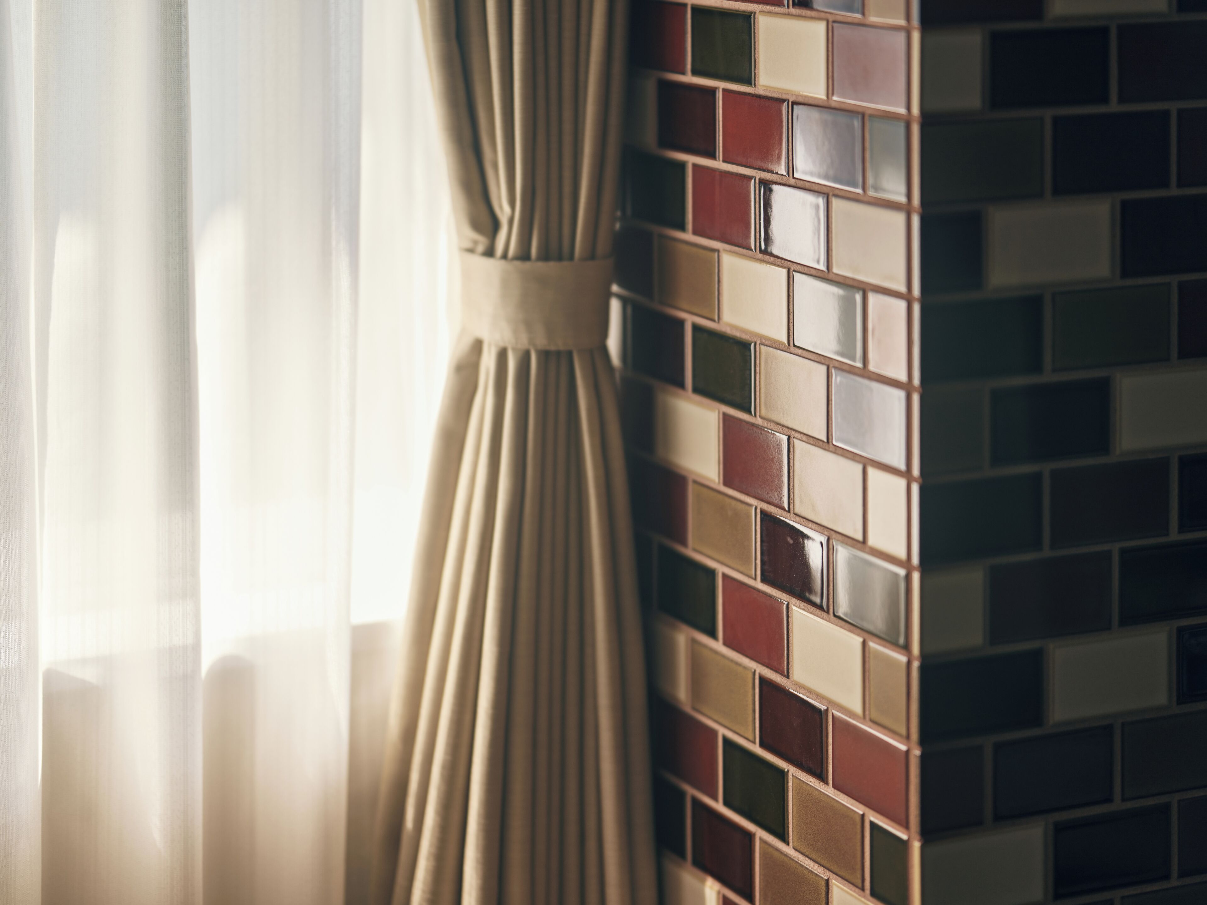 A room with a curtain and a tiled wall.