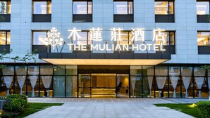 The Mulian Hotel with a modern facade, large glass entrance, and a well-maintained outdoor area. - Mulianzhuang Hotel FrontierMedicalCenter (Chengdu)