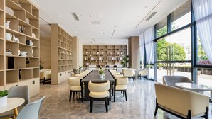 A spacious conference room with a long table and chairs, surrounded by bookshelves and large windows. - Mulianzhuang Hotel FrontierMedicalCenter (Chengdu)