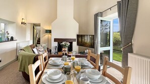 Un coin repas avec une table mise pour le petit-déjeuner, une cheminée et une vue sur l’extérieur.