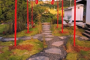 A garden pathway with red poles, a white building, and a stone-tiled area. - Sirine Onsen (Khao Kho)