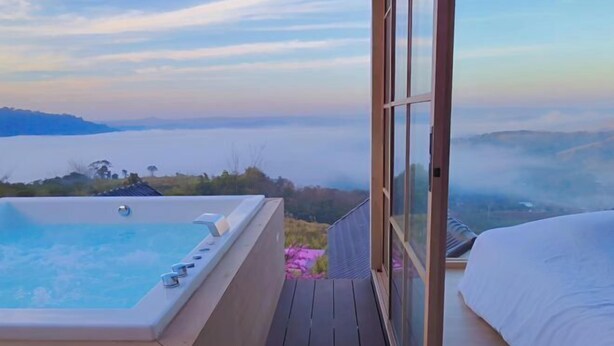 Ein Balkon mit Whirlpool, Bett und Blick auf eine Berglandschaft.