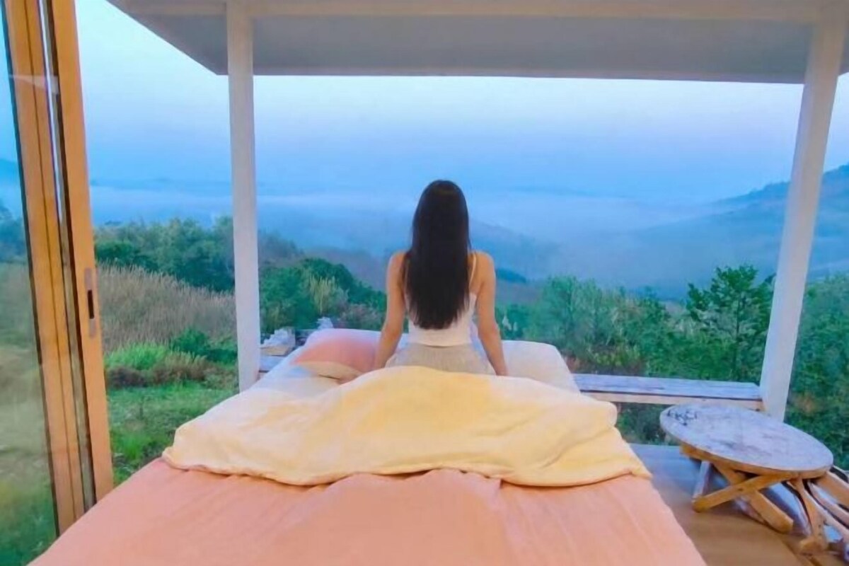 Une personne est assise sur une table de massage, avec une vue sur un paysage montagneux.
