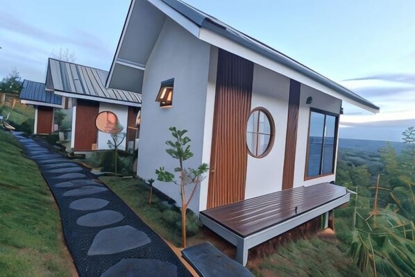 A modern house with a sloped roof, a circular window, and a wooden deck. - Sirine Onsen (Khao Kho)