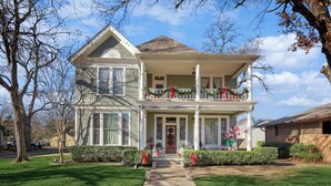 Une maison à deux étages avec un porche à l’avant, décoré de guirlandes et de décorations de Noël.