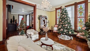 Un salon spacieux, agrémenté d’un grand sapin de Noël, de meubles élégants et d’un lustre.