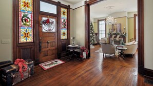 Un intérieur traditionnel avec une porte en bois, des vitraux, une couronne de Noël et un lustre.