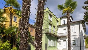 A building with a green facade, white shutters, and a balcony with a wrought iron railing. - Le Gemme by Interhome (Meina)