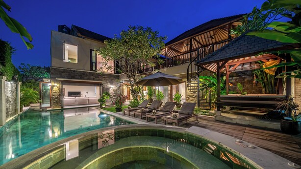 A modern villa with a swimming pool, outdoor seating, and a covered patio area.