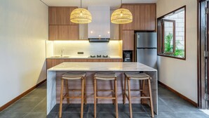 A modern kitchen with a central island, wooden cabinets, and pendant lighting.
