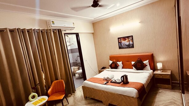 A hotel room with a bed, a chair, a small table, a nightstand, and a ceiling fan.