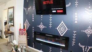 A wall-mounted television displaying a Netflix interface, a fireplace, and decorative wall patterns.
