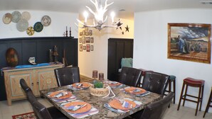 A dining area with a marble table set for six, surrounded by leather chairs.