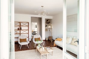 Ein modernes Wohnzimmer mit einer Couch, zwei Sesseln, einem Couchtisch, einer Chandelier und einem Bücherregal.