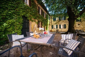 An outdoor patio with a table set for two, surrounded by metal chairs with striped cushions.