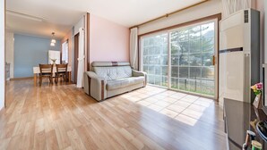 A spacious living area with a sofa, a dining table with chairs, and a large sliding glass door leading to a balcony. - Yeongwol Nature & Retreat (Yeongwol)