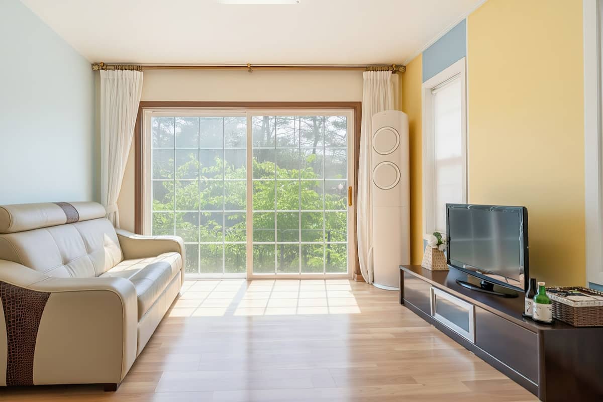 A living room with a sofa, a TV, and a sliding glass door leading to a balcony.