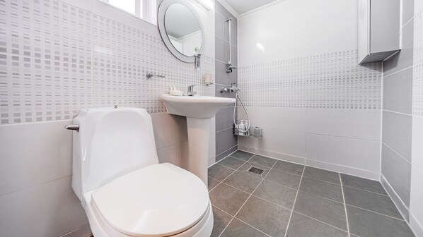 Un baño moderno con inodoro, lavamanos y ducha.