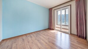 A room with light blue walls, wooden flooring, and a large sliding glass door leading to a balcony. - Yeongwol Nature & Retreat (Yeongwol)