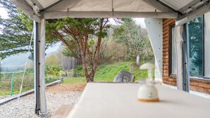 A covered outdoor seating area with a view of a hillside and trees. - Yeongwol Nature & Retreat (Yeongwol)