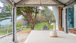 A covered outdoor seating area with a view of a hillside and trees. - Yeongwol Nature & Retreat (Yeongwol)