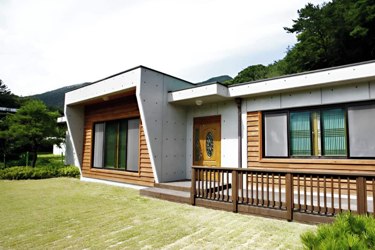 A modern building with a wooden deck, large windows, and a blue sign indicating a specific location.
