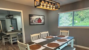 A dining area with a dark wooden table, white chairs, and woven placemats.