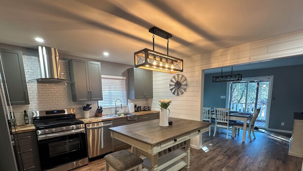 A modern kitchen with stainless steel appliances, a wooden island, and a dining area with a view.