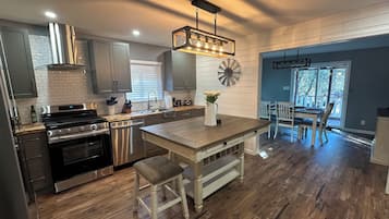 Une cuisine moderne dotée d’appareils électroménagers en acier inoxydable, d’un îlot central en bois et d’un coin repas offrant une vue agréable.