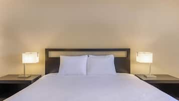 A neatly made bed with white linens and two bedside lamps on matching nightstands.