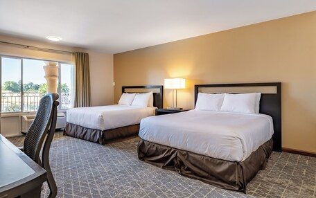 A hotel room with two beds, a desk, and a chair.