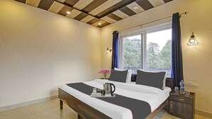 A bedroom with a wooden bed, a nightstand, a window with curtains, and a wall-mounted light fixture. - Himalayan View stay (Mussoorie)