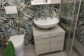 A bathroom with a white sink, a toilet, and a shower.