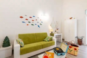 Una sala moderna con un sofá verde, un pequeño árbol de Navidad y una decoración de peces en la pared.