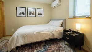 Ein Schlafzimmer mit einem Bett, einem Nachttisch, einer Lampe und drei gerahmten Bildern an der Wand.
