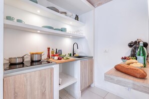 A modern kitchen with a built-in stove, a sink, and a countertop with various kitchen items.