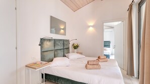Un dormitorio moderno con una cama grande, una mesita de noche, un espejo y vista al baño.