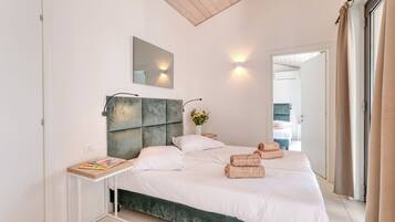Une chambre moderne avec un grand lit, une table de chevet, un miroir et une vue sur la salle de bain.